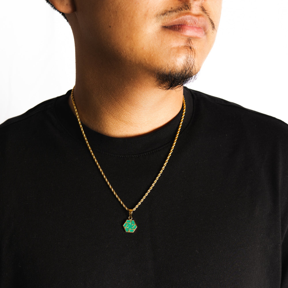 Man wearing a black shirt with a gold chain and green pendant