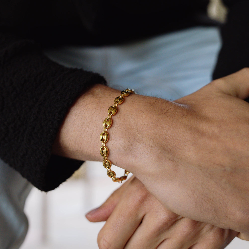 Gold chain bracelet on a wrist with a blurred background