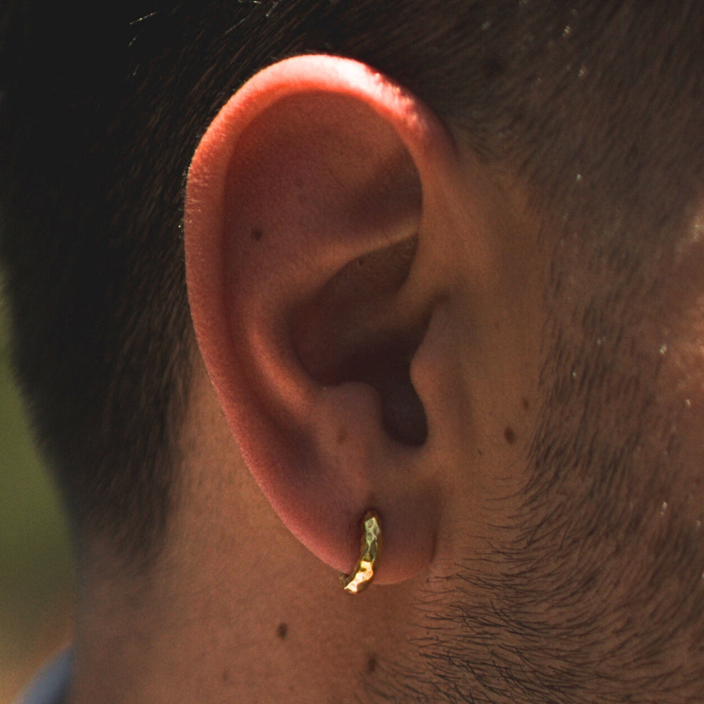 Close-up of a person's ear with a gold earring.