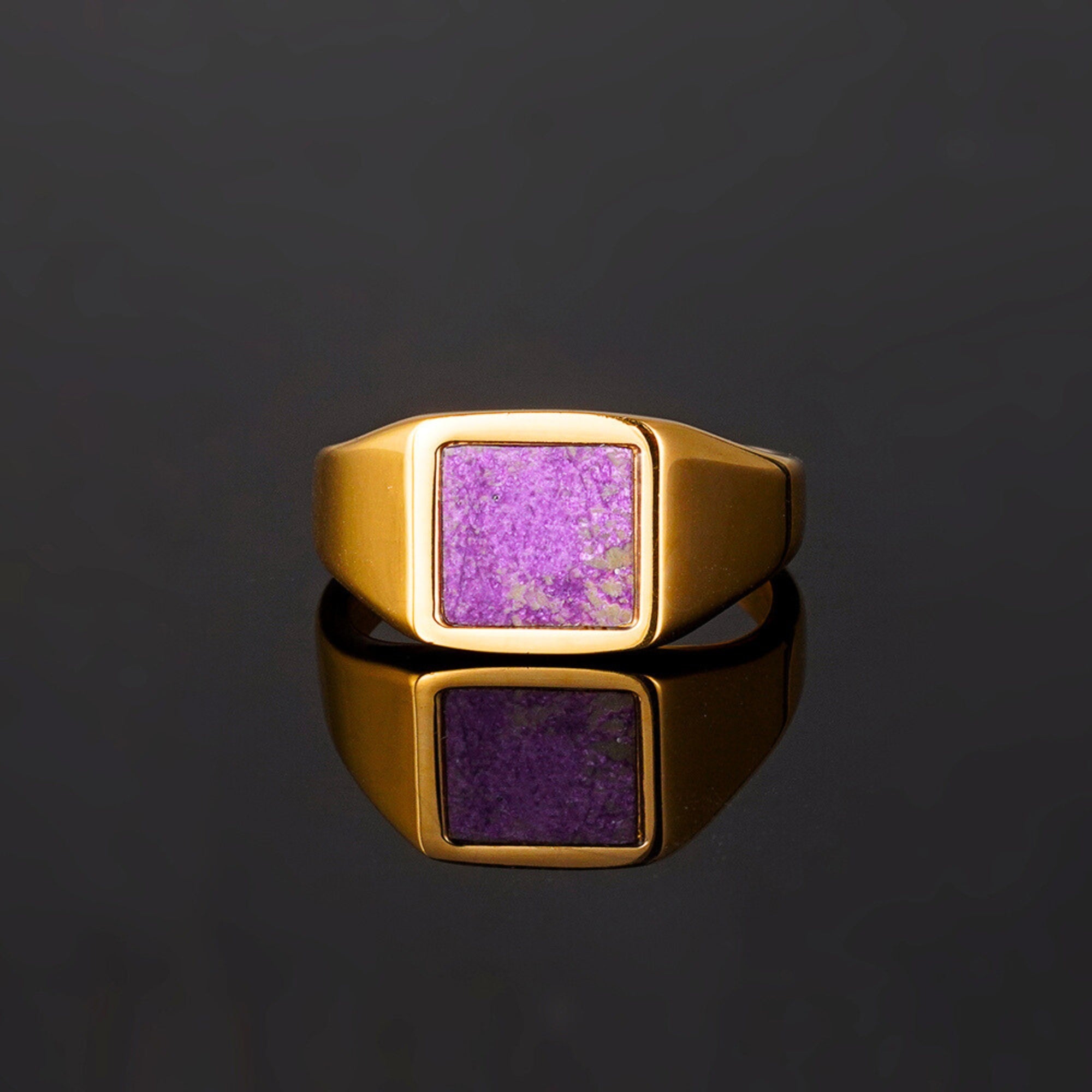 Gold ring with a purple stone on a black background