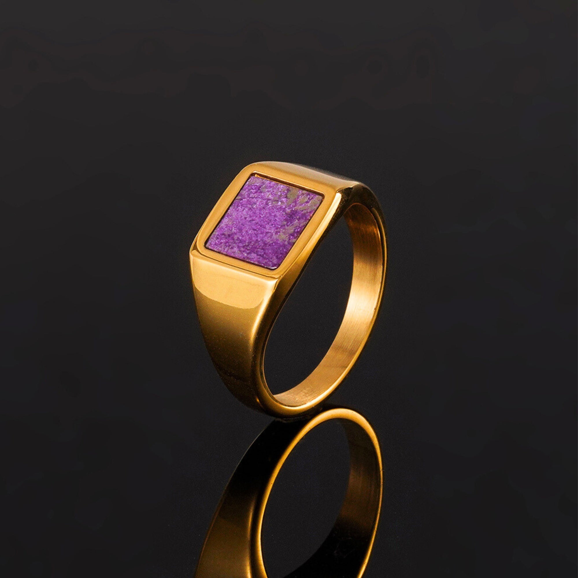 Gold ring with a purple stone on a black background