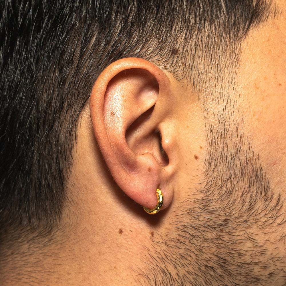 Close-up of a person's ear wearing a gold hoop earring.