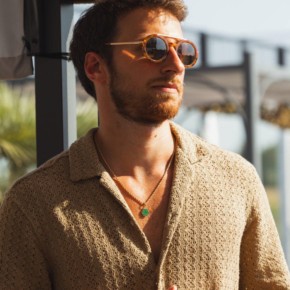 Man wearing sunglasses and a beige shirt outdoors