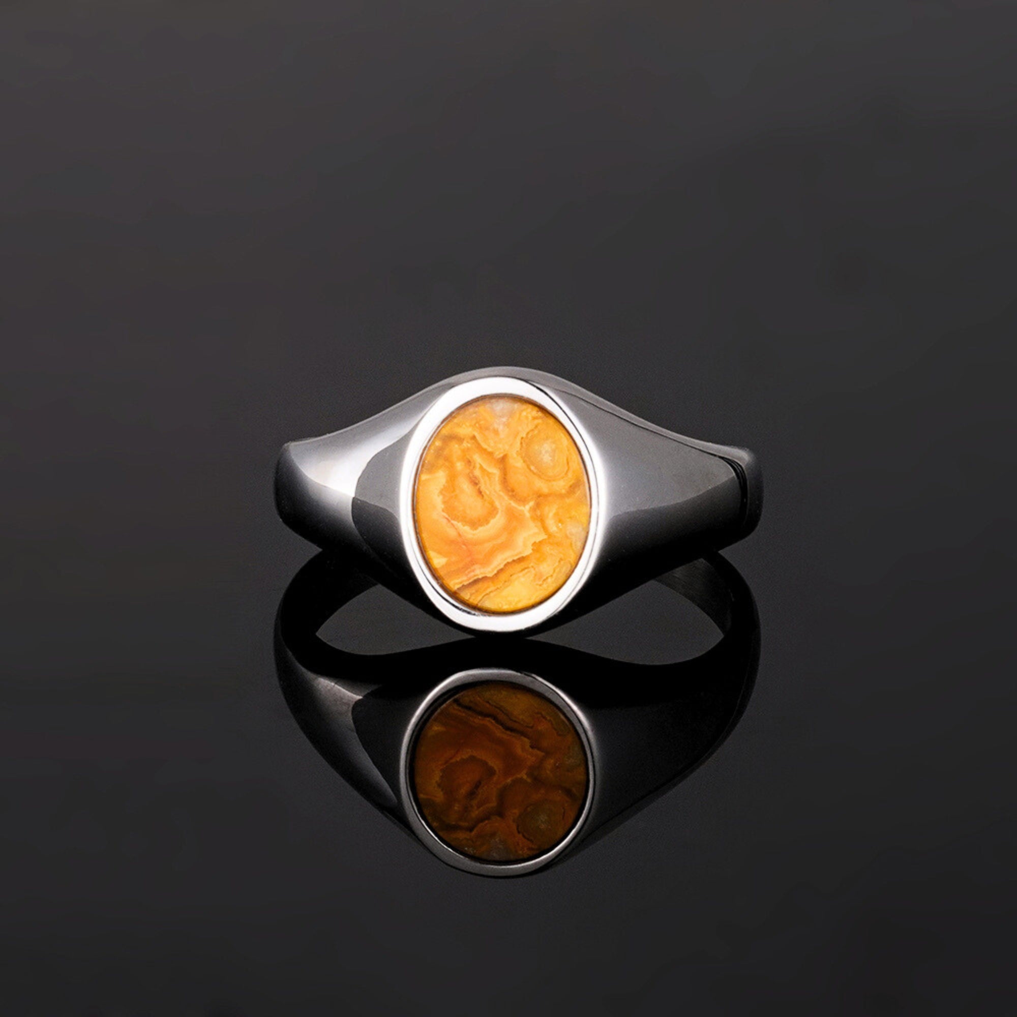 Silver ring with a yellow stone on a black background