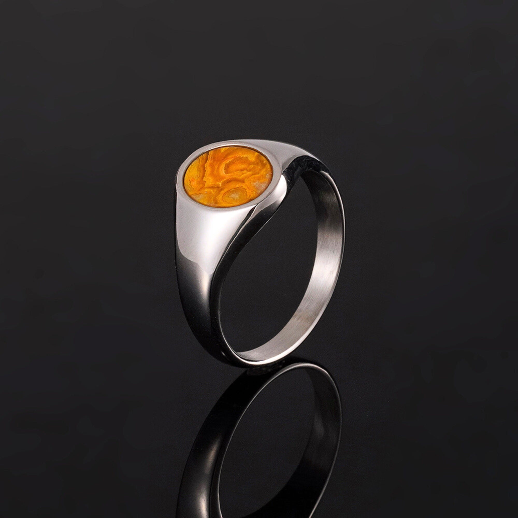 Silver ring with a yellow stone on a black background