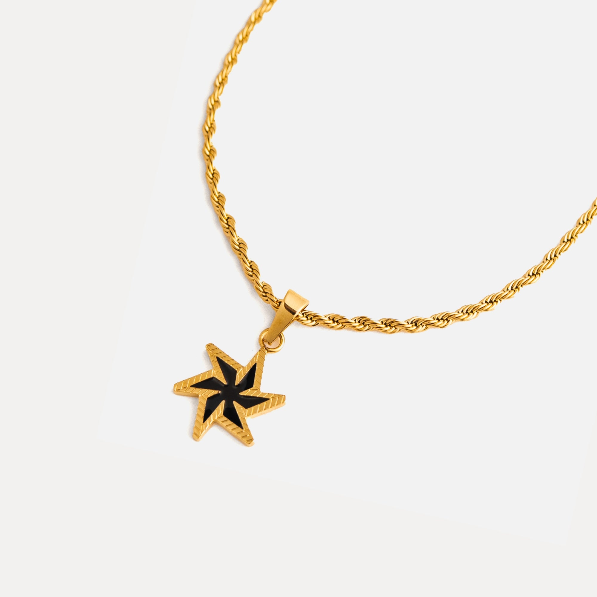 Gold necklace with a star-shaped pendant on a white background