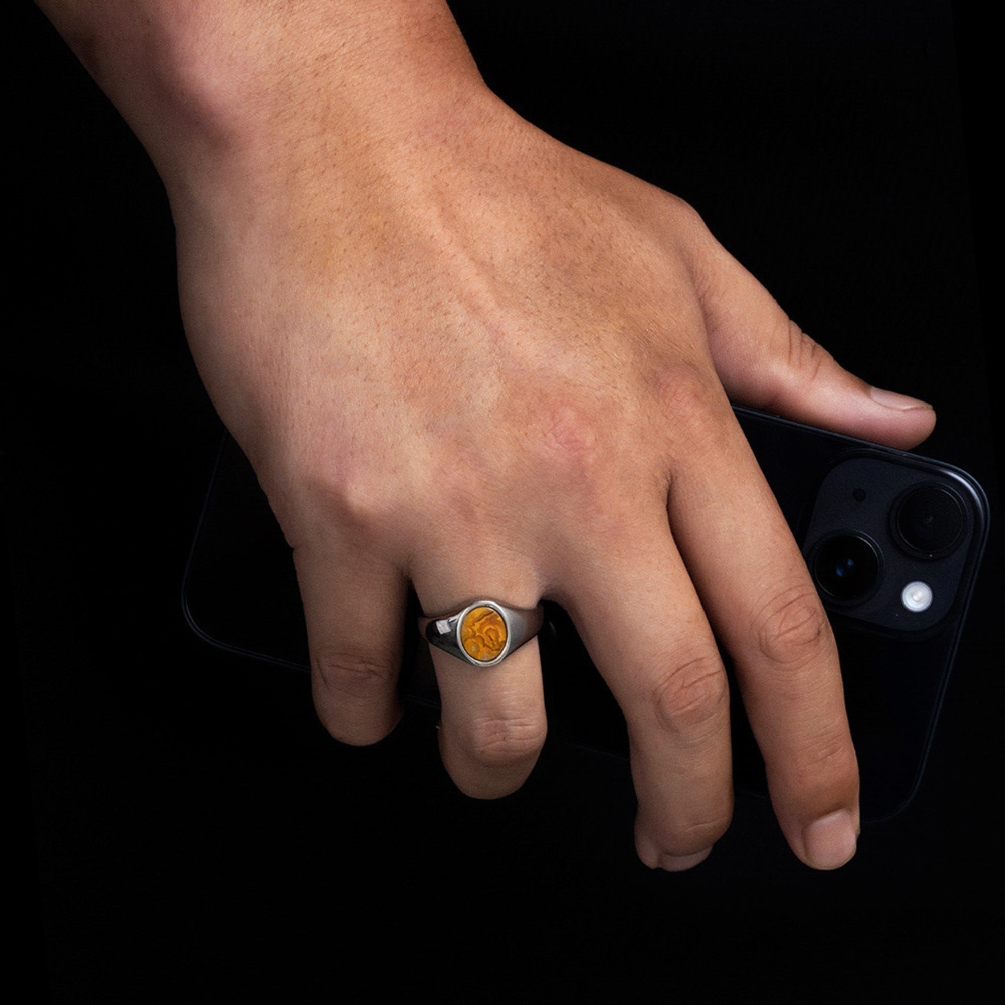Hand wearing a ring with a black background