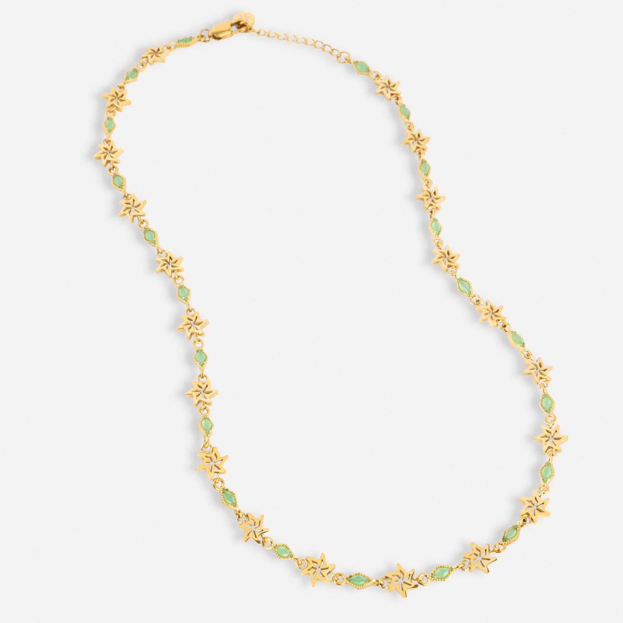 Gold necklace with green gemstones on a white background