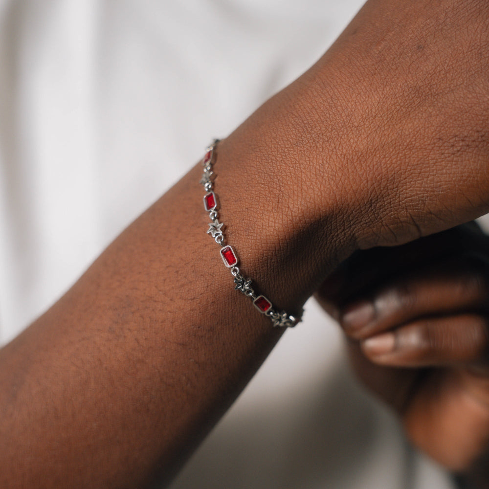 Bracelet with red stones on a wrist against a neutral background