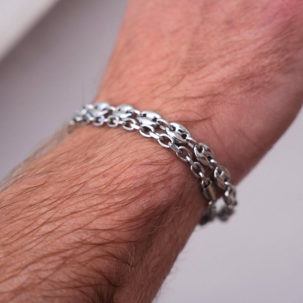 Silver chain bracelet on a wrist with a neutral background