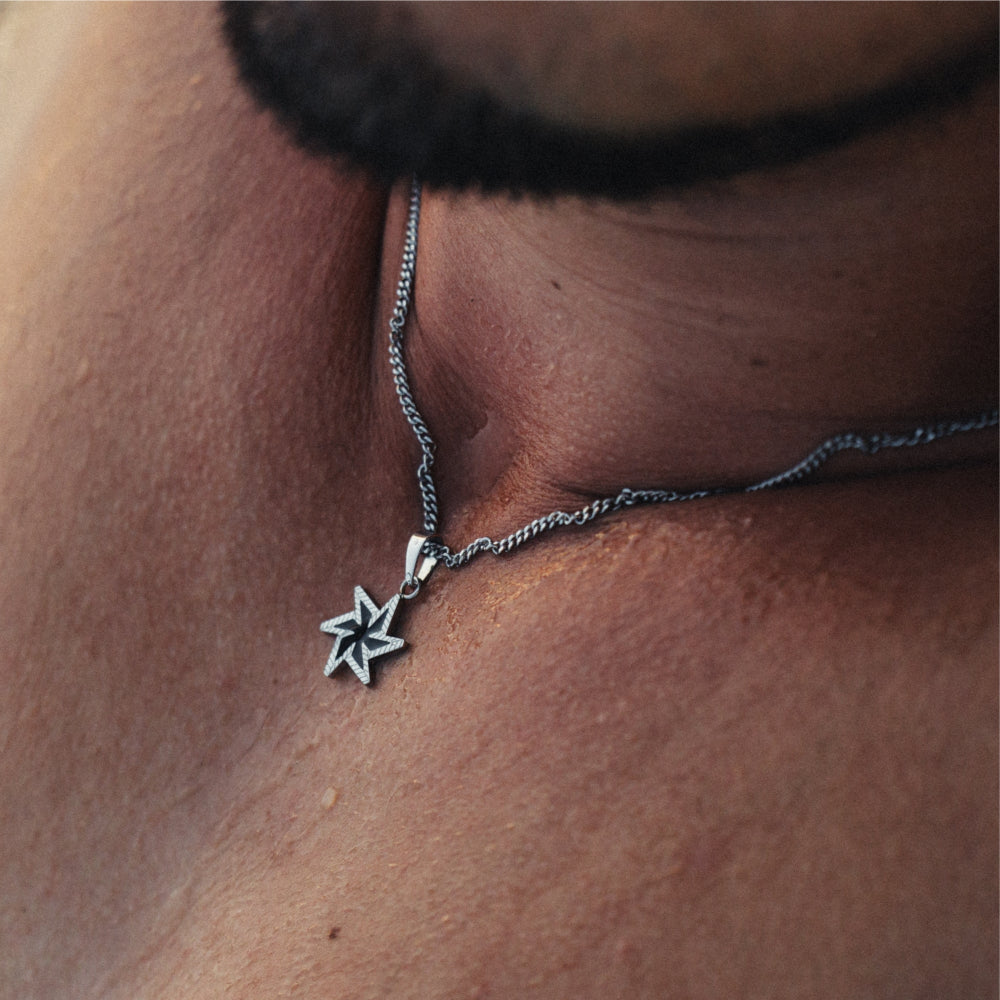 Silver star-shaped pendant on a chain against a skin background