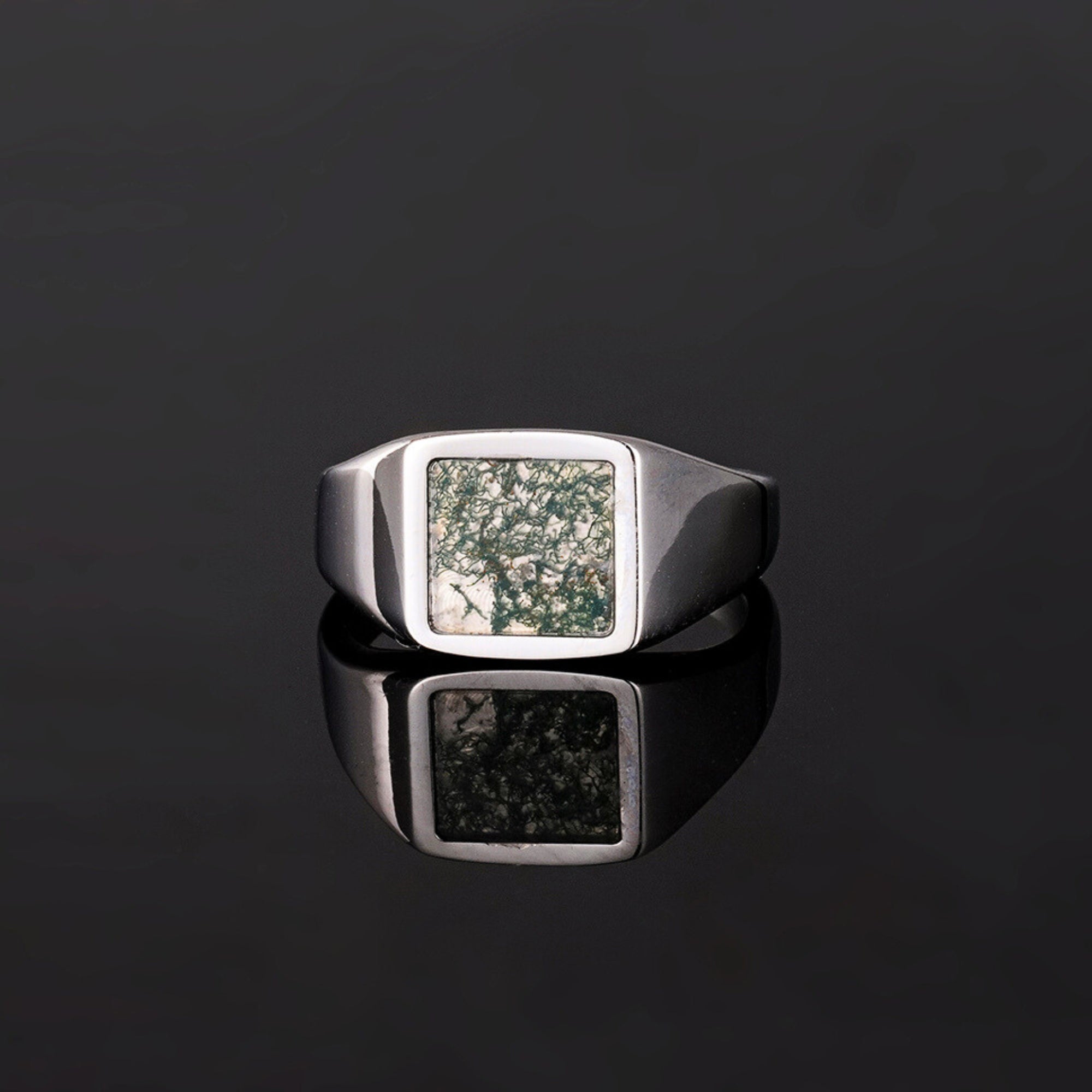 Silver ring with a textured square stone on a black background