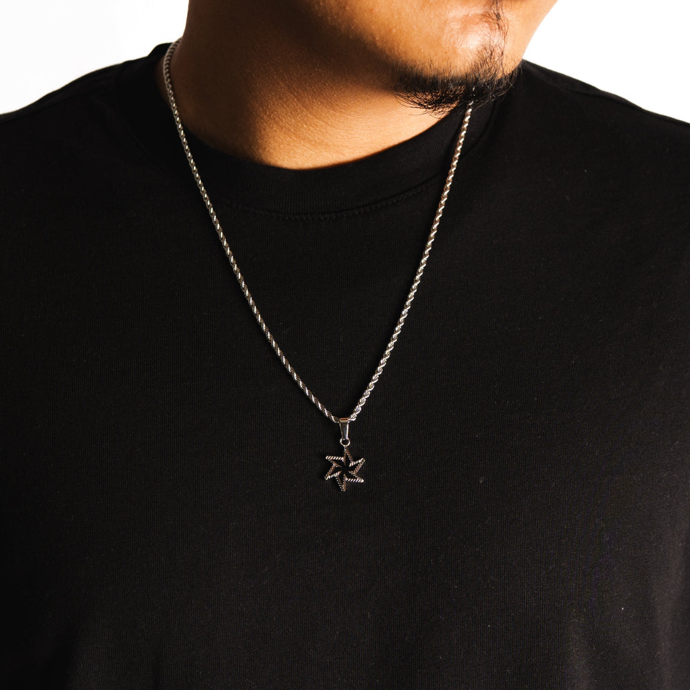 Person wearing a black shirt with a silver chain necklace featuring a star pendant.