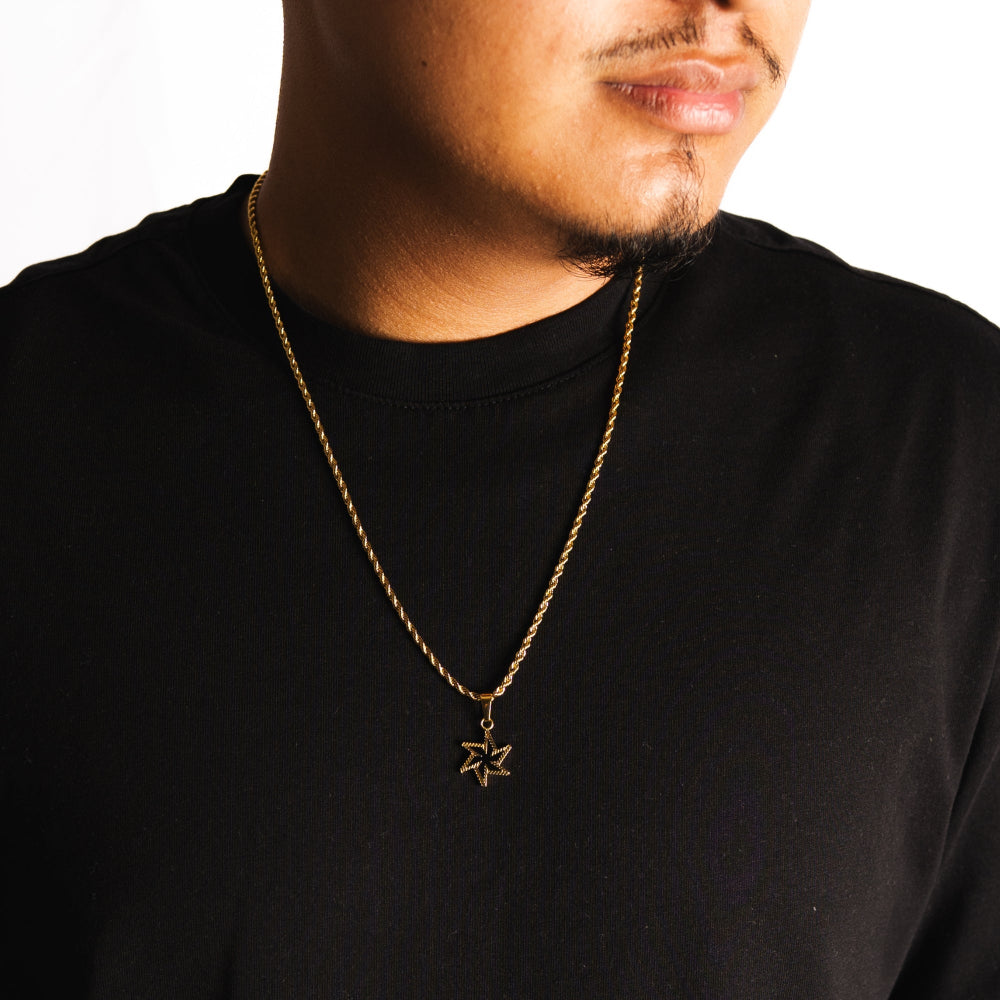 Man wearing a black shirt with a gold necklace featuring a star pendant.