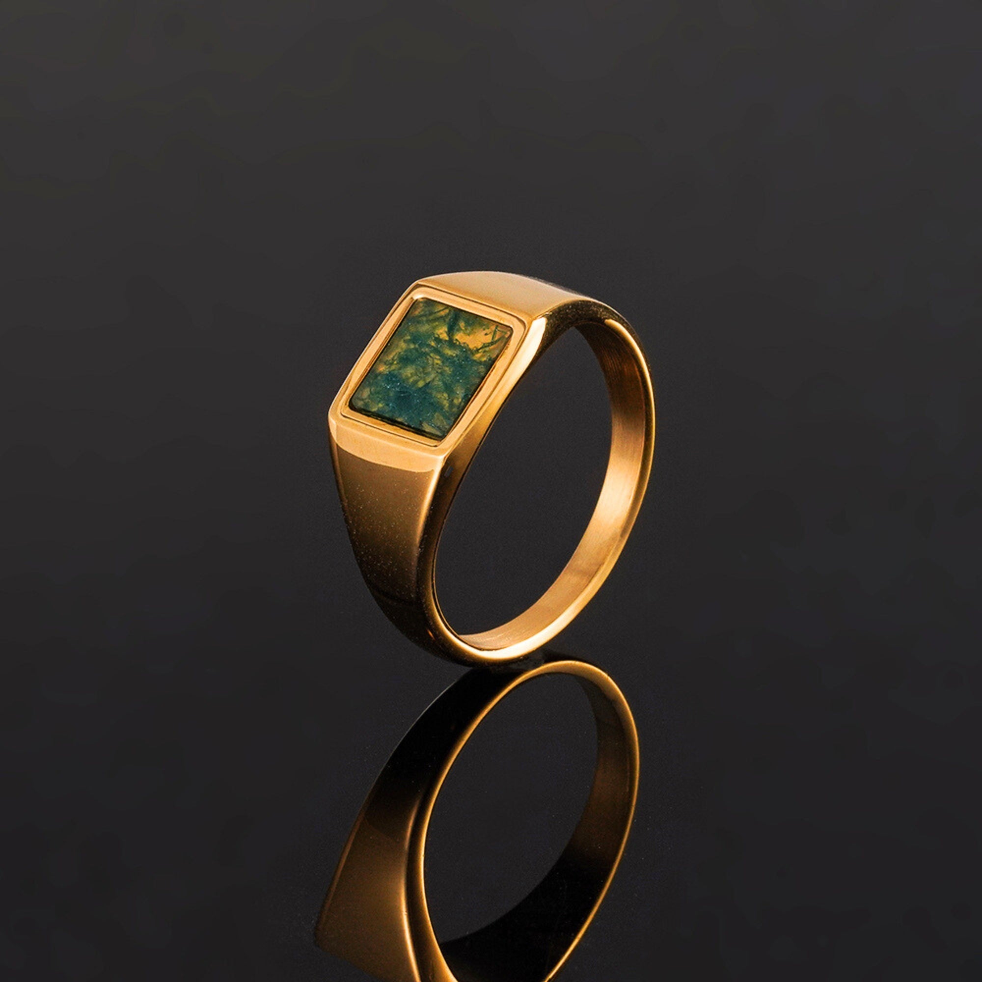 Gold ring with a green stone on a black background