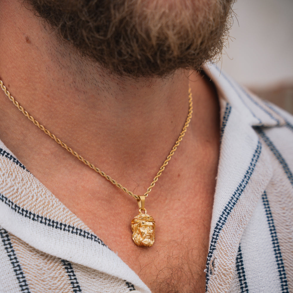 Gold necklace with a pendant worn by a person, close-up on neck and shoulders.