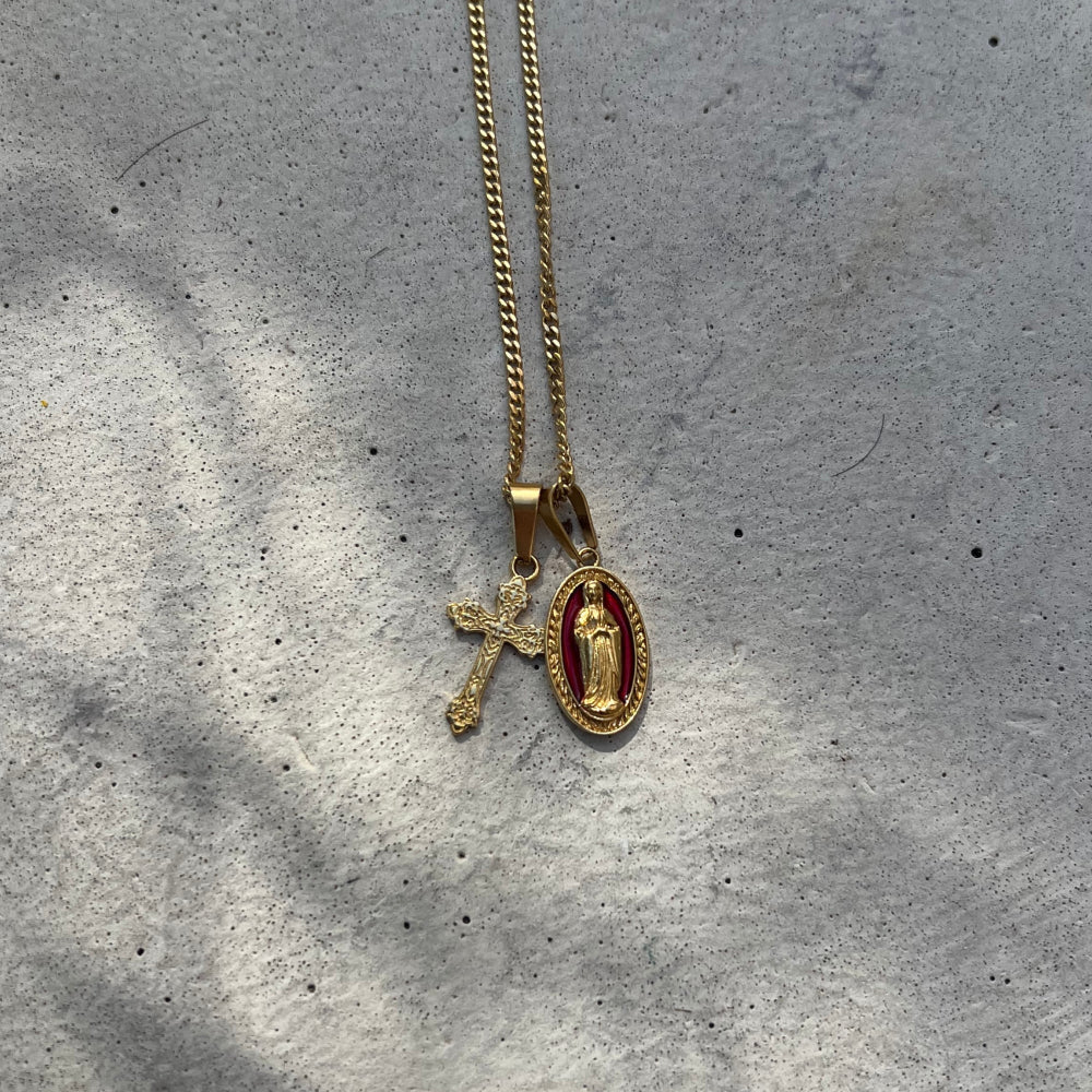 Gold necklace with two pendants on a gray concrete surface