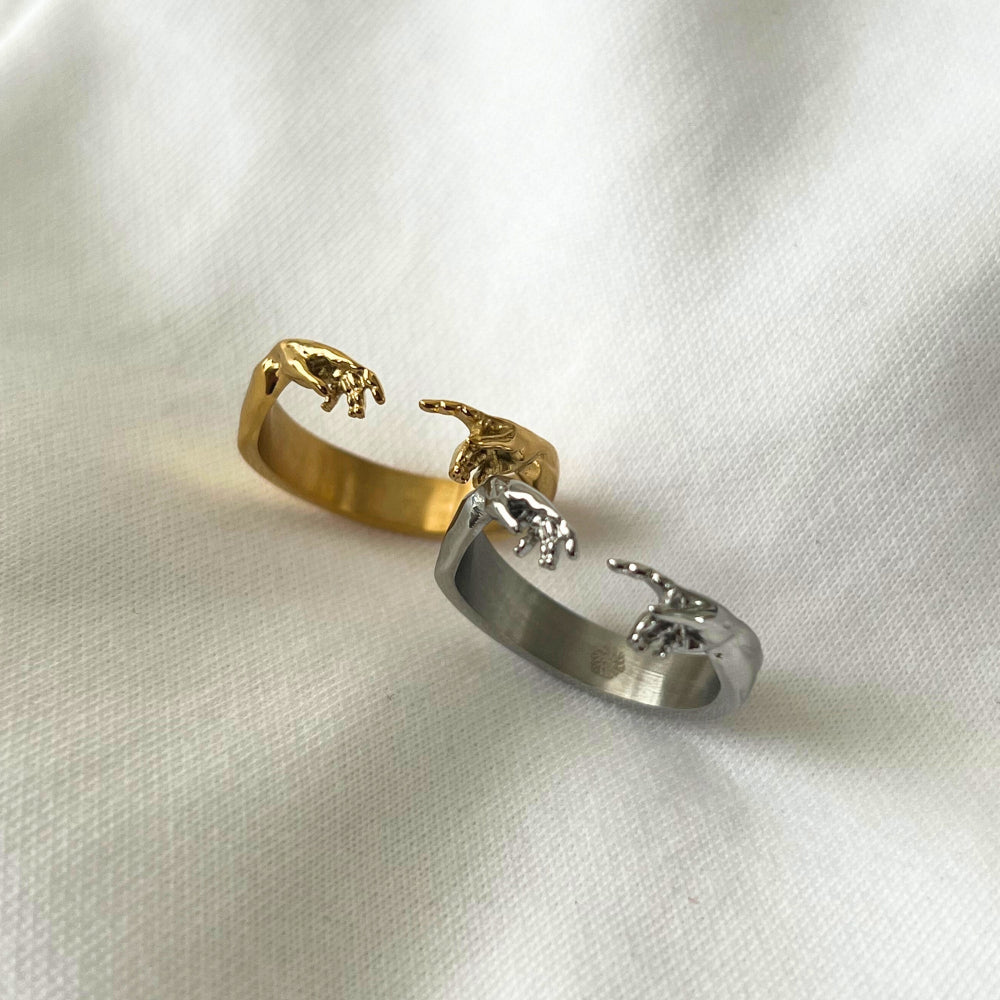 Gold and silver rings with animal designs on a white fabric background