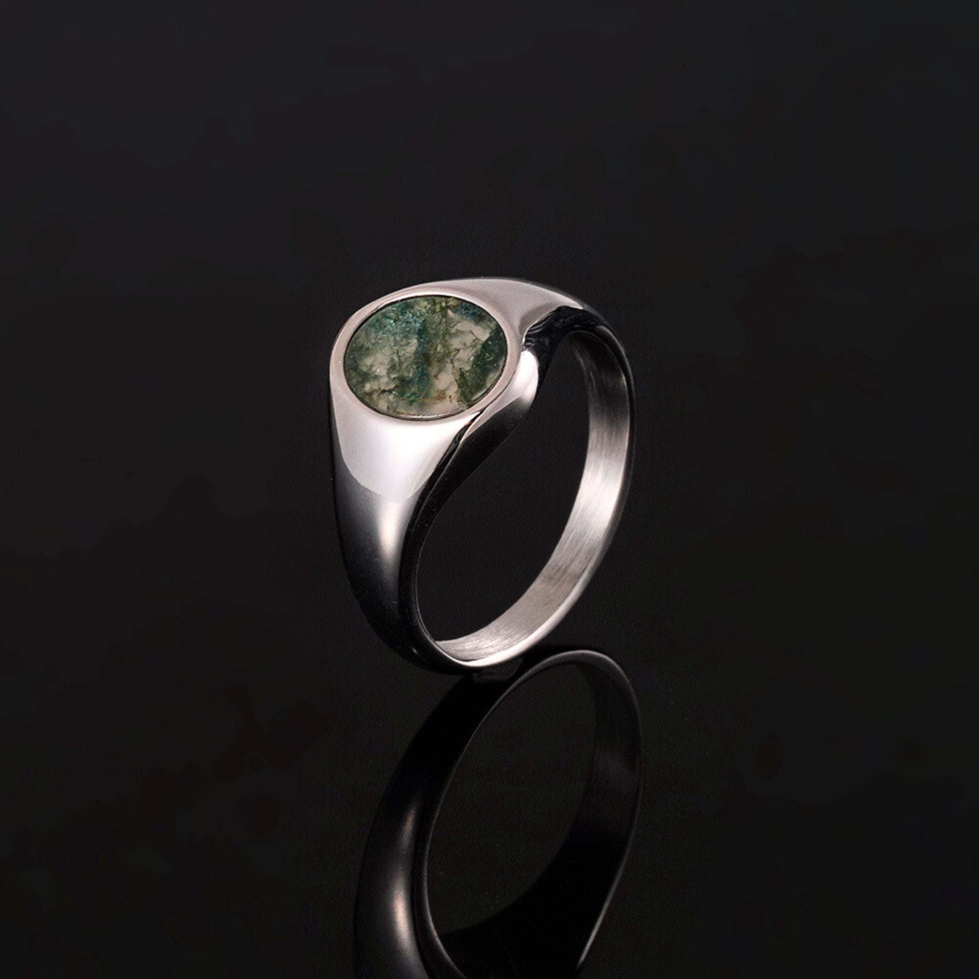 Silver ring with a green stone on a black background