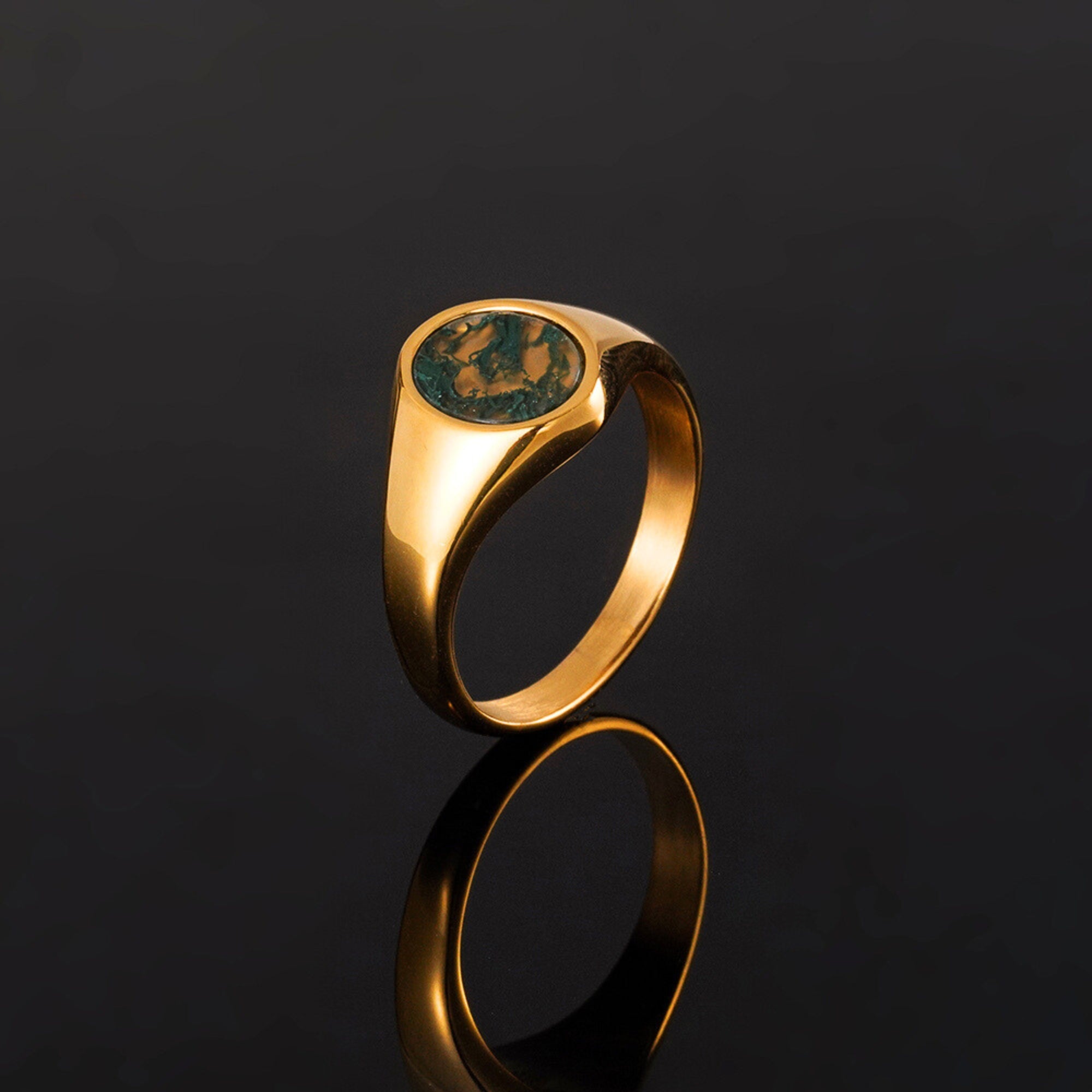 Gold ring with a green stone on a black background