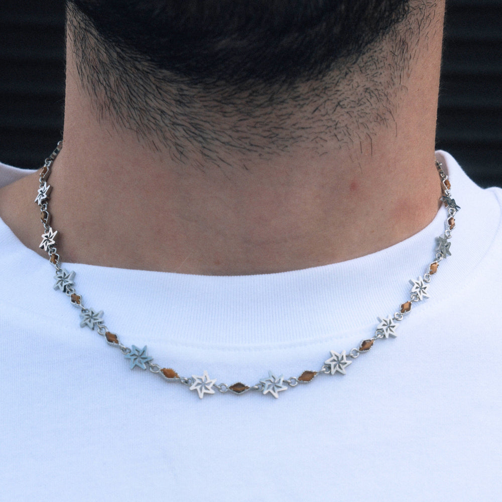Necklace with star-shaped beads worn by a person on a plain background