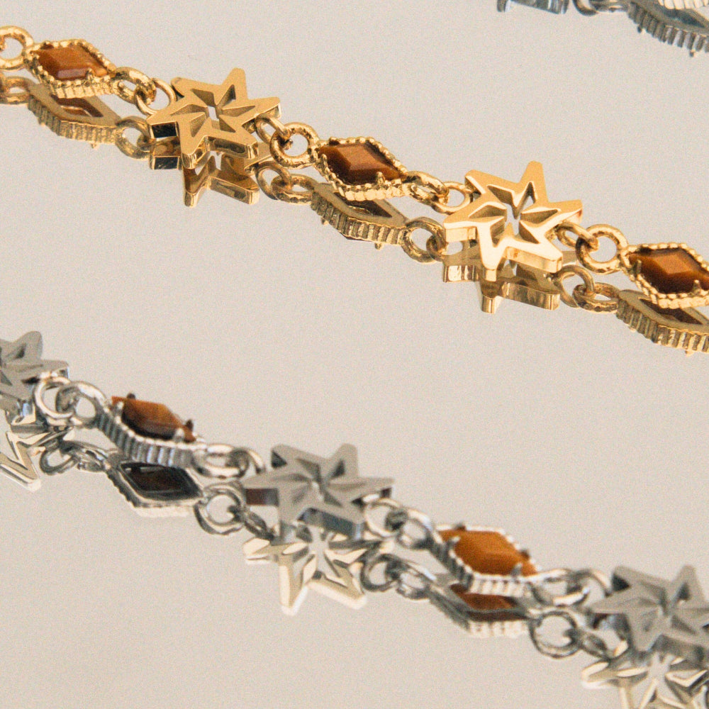 Gold and silver bracelet with star-shaped links on a light gray background