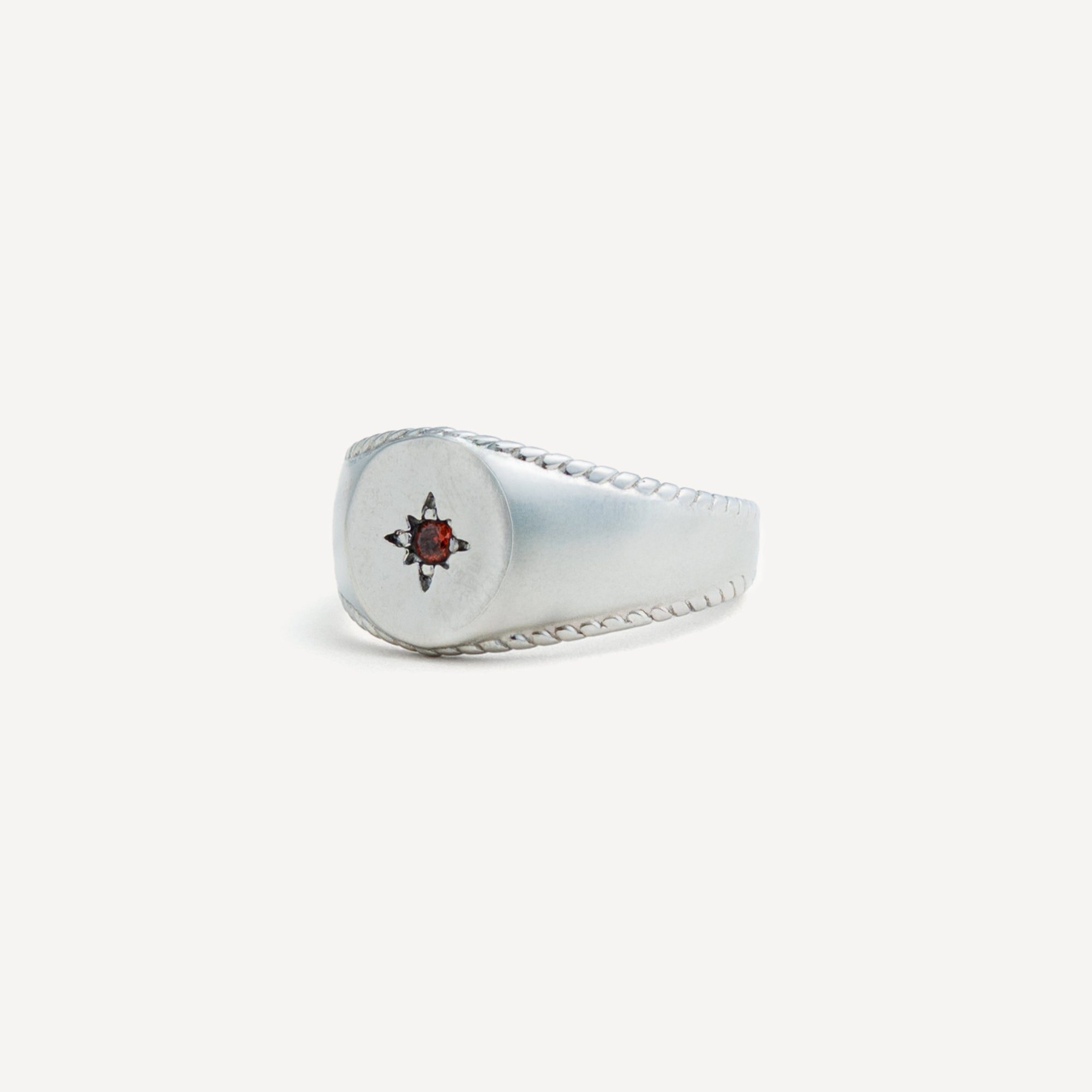 Silver ring with a red gemstone on a white background