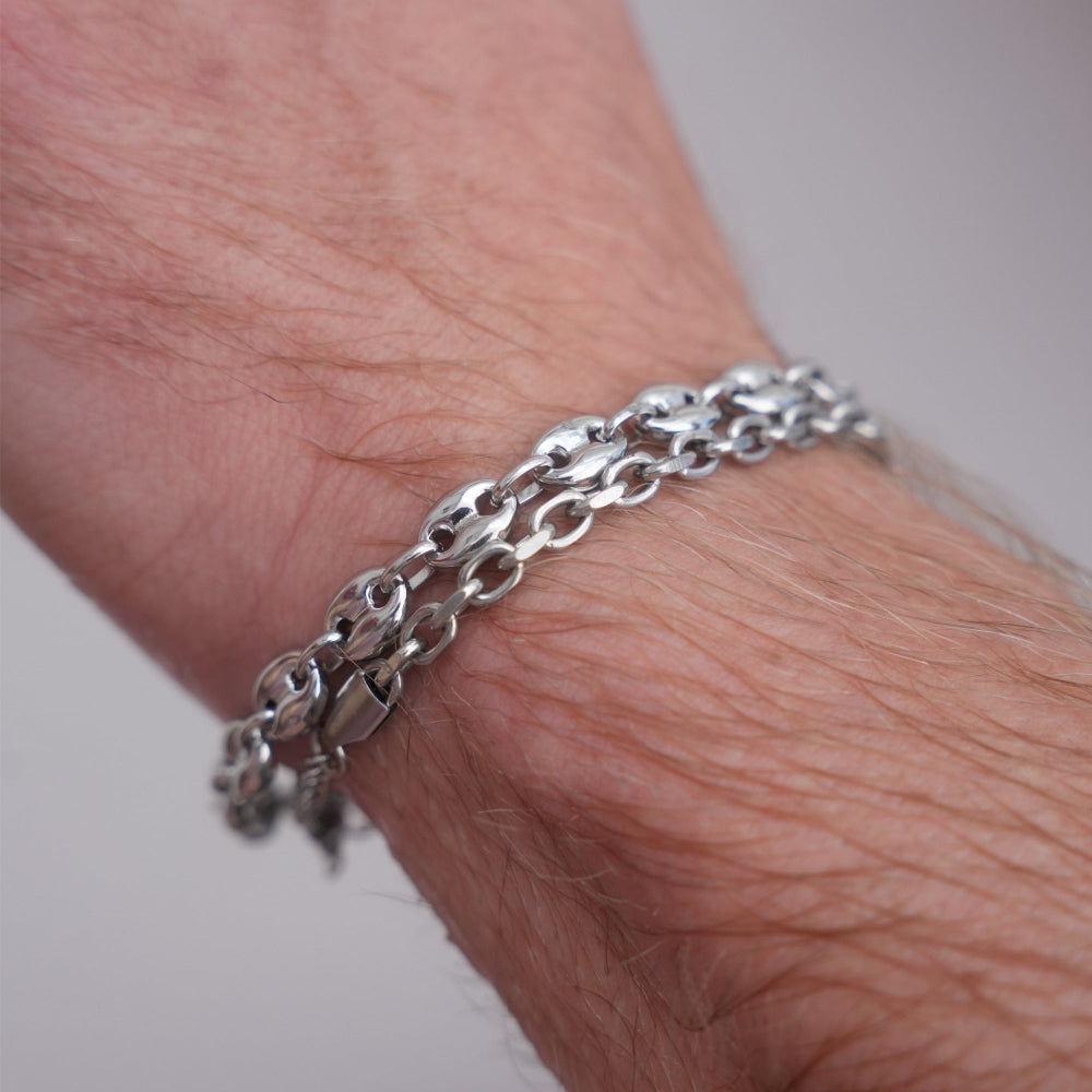 Silver chain bracelet on a wrist with a plain background