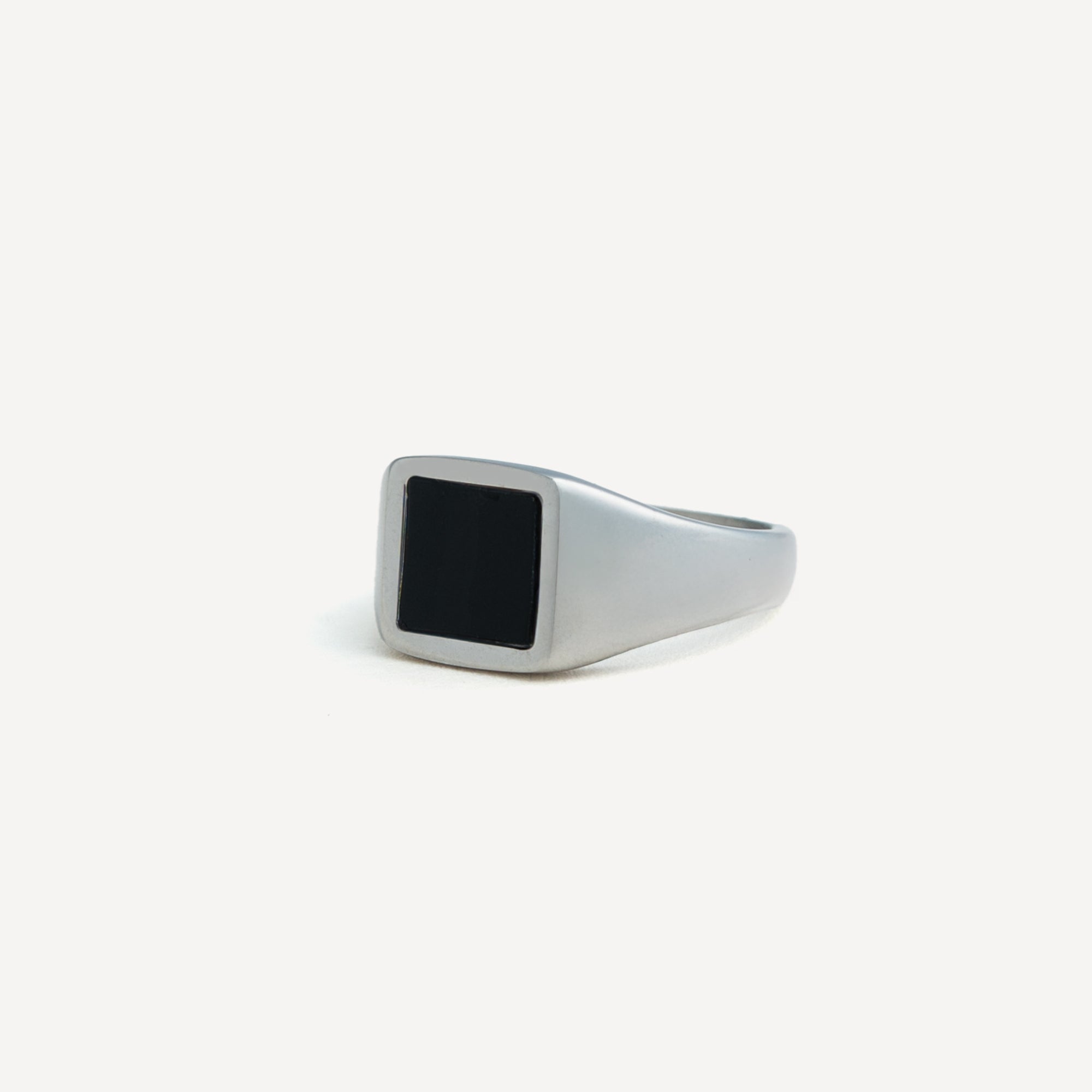 Silver signet ring with a black stone on a white background