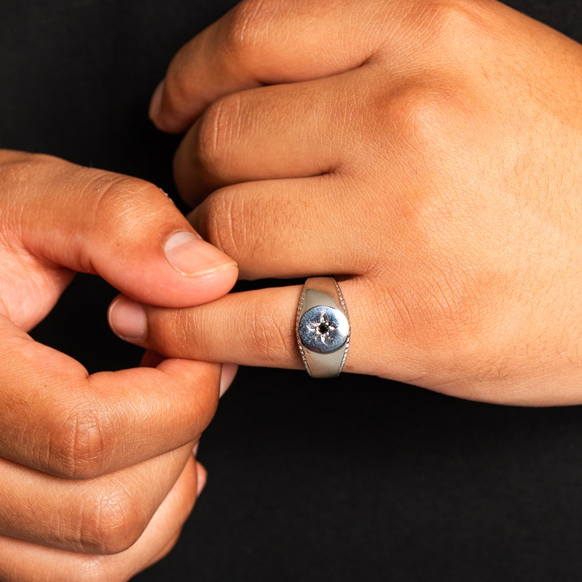 Close-up of a hand wearing a ring with a dark background