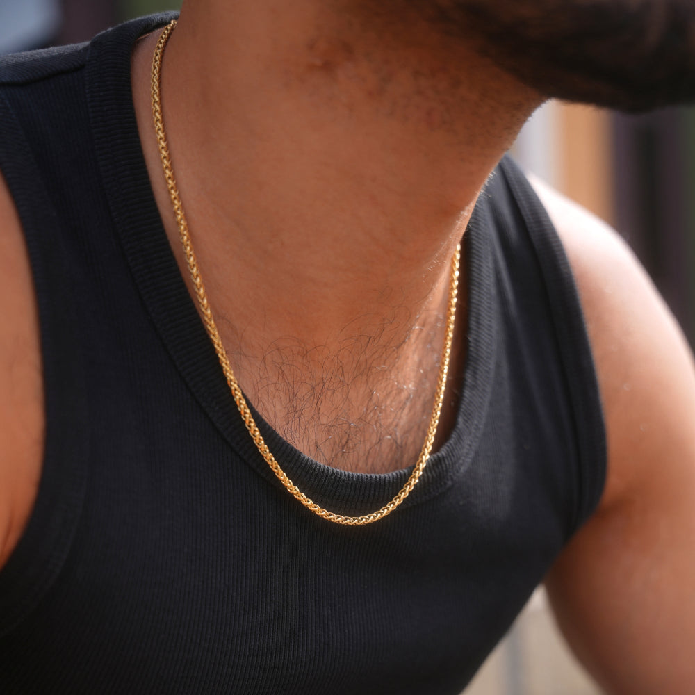 Person wearing a gold chain necklace with a blurred background