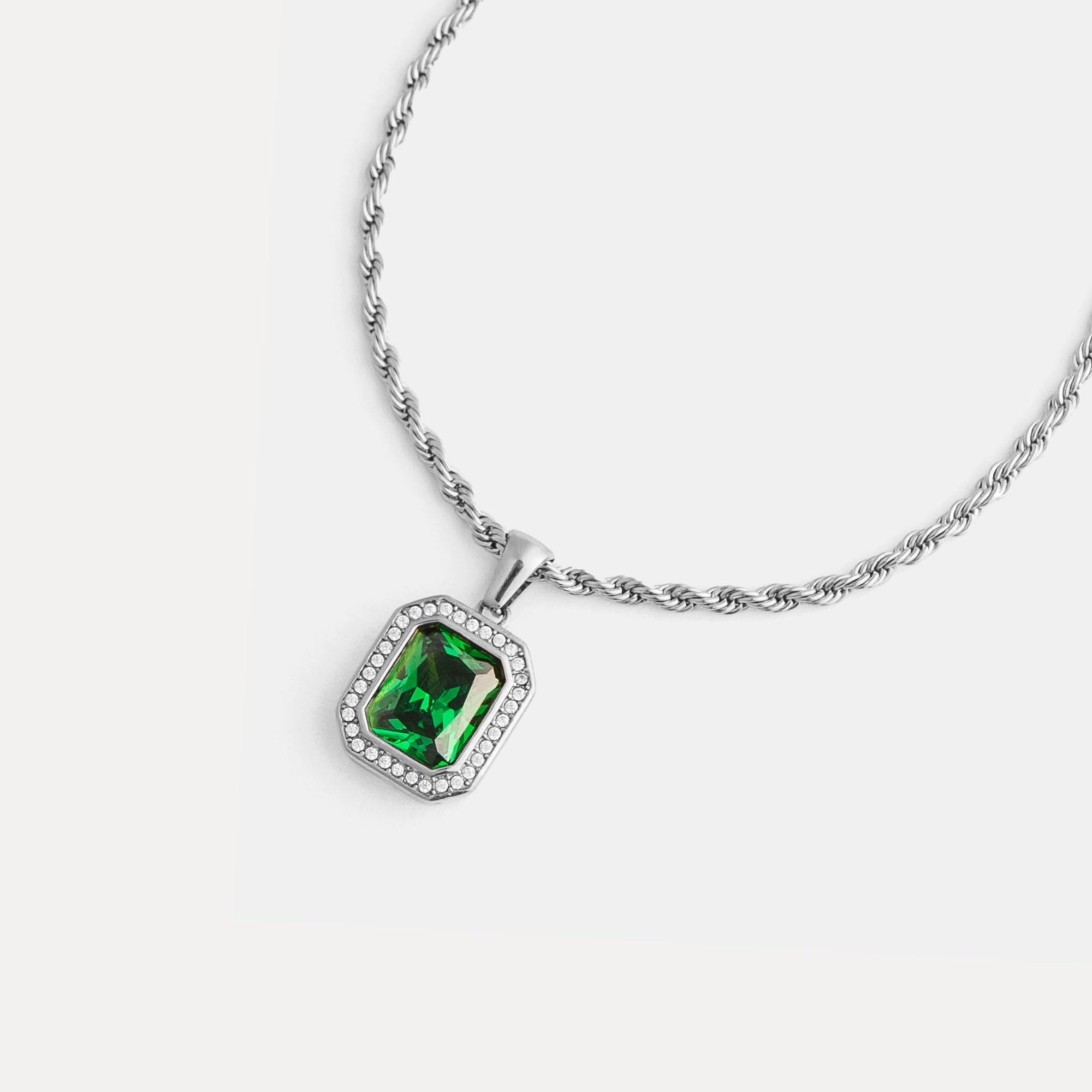 Silver necklace with a green gemstone pendant on a white background