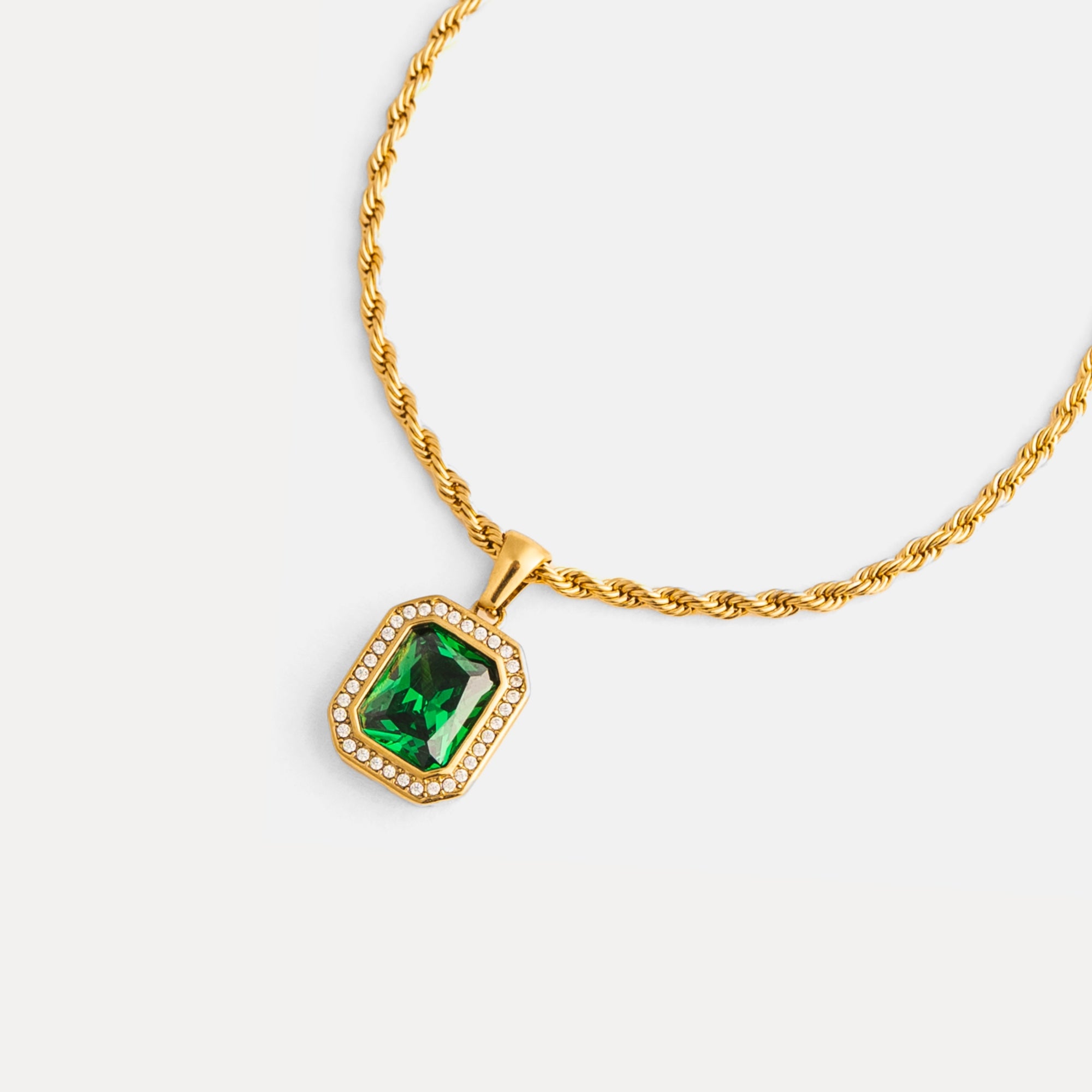 Gold necklace with a green gemstone pendant on a white background