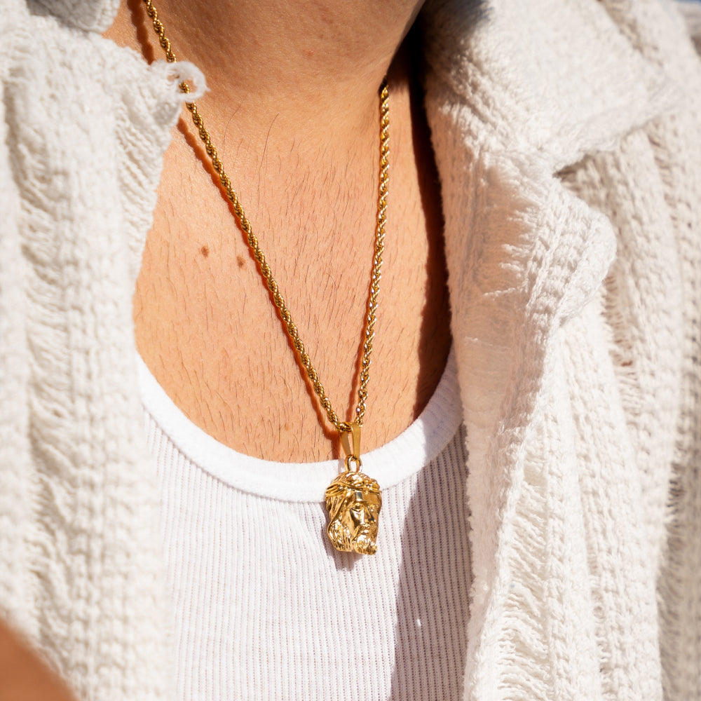 Gold necklace with a pendant worn by a person against a white background
