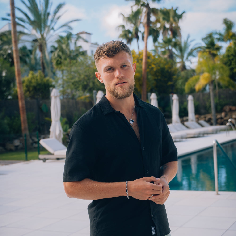 Man standing by a pool with palm trees in the background