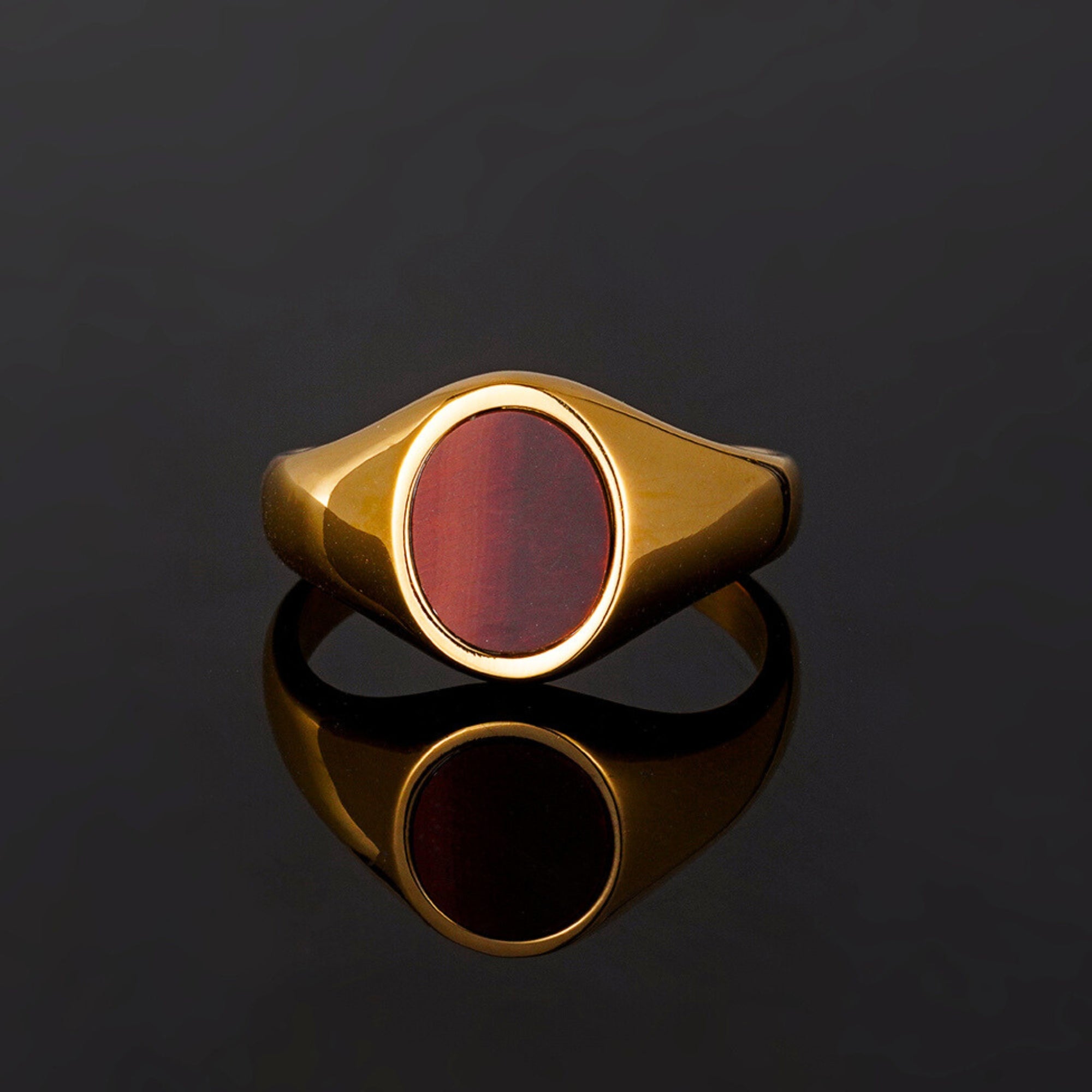 Gold ring with a red stone on a black background