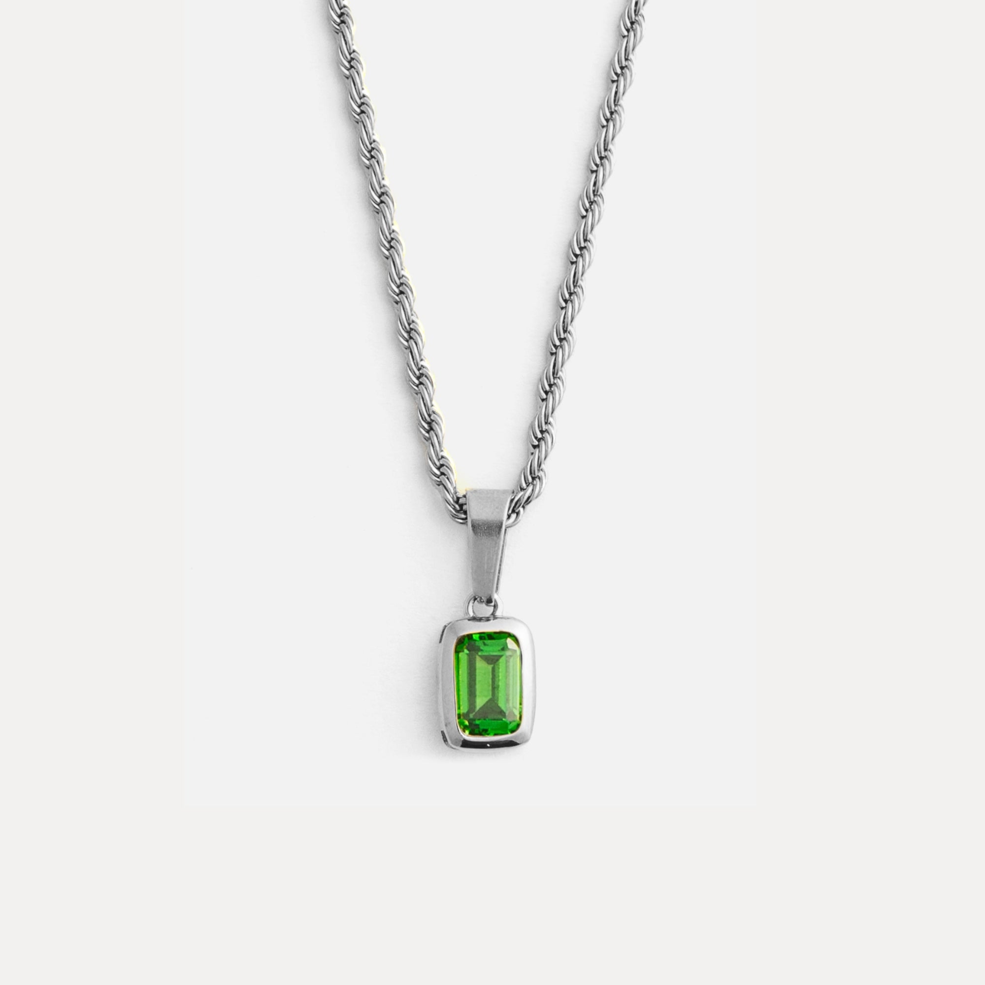 Silver necklace with a green gemstone pendant on a white background