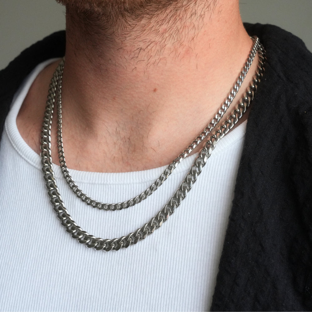 Person wearing a double chain necklace on a plain background