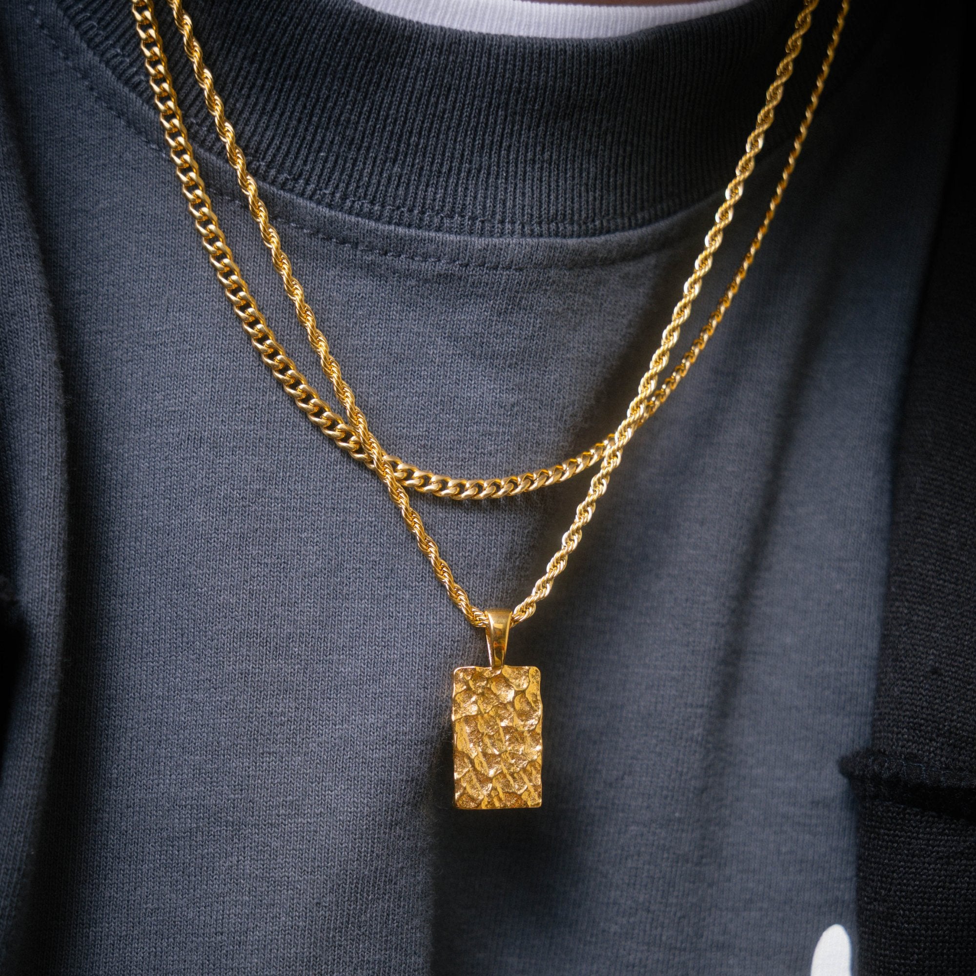 Gold chain necklace with pendant on black shirt