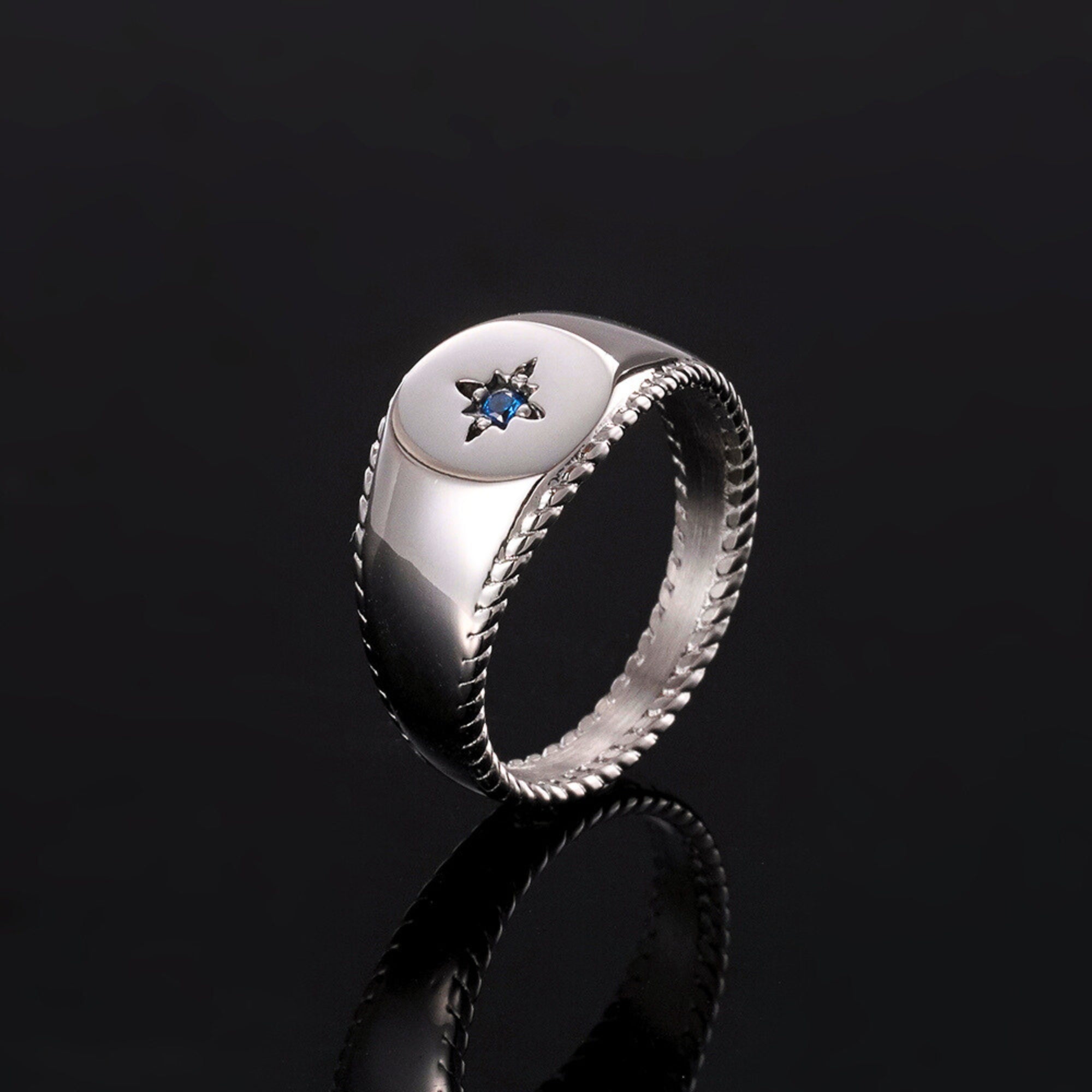 Silver ring with a blue gemstone on a black background