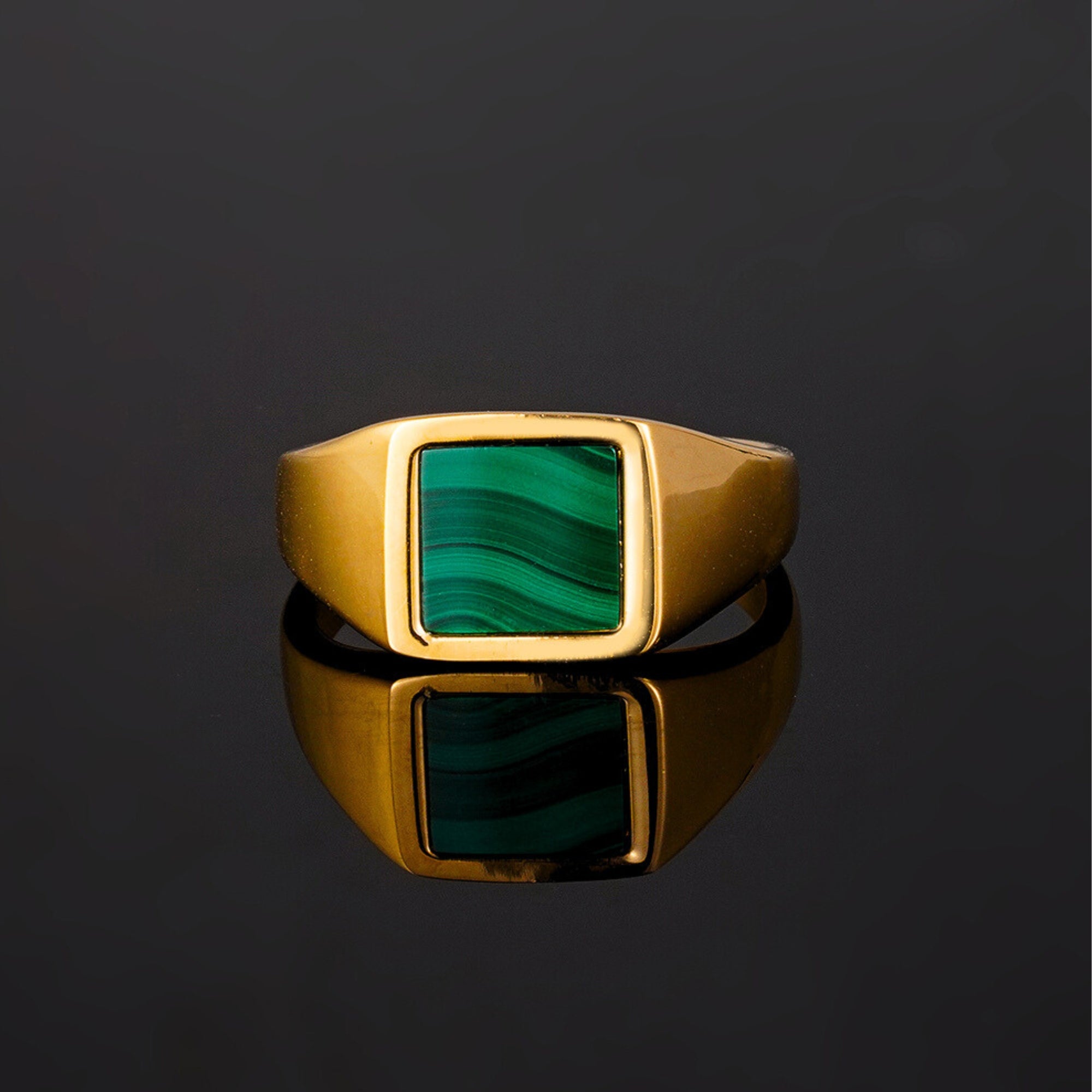 Gold ring with a green stone on a black background
