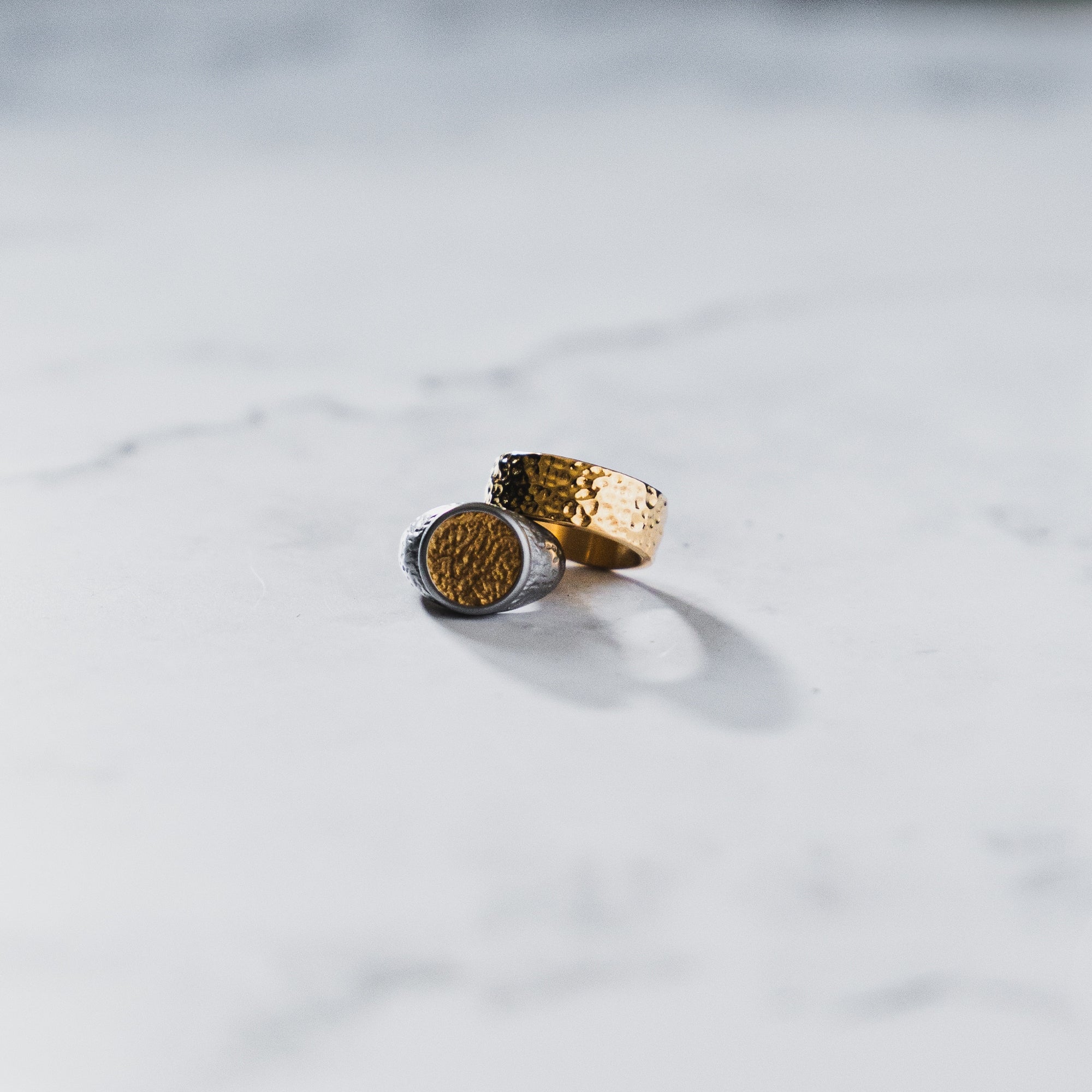 Two gold rings on a light gray surface