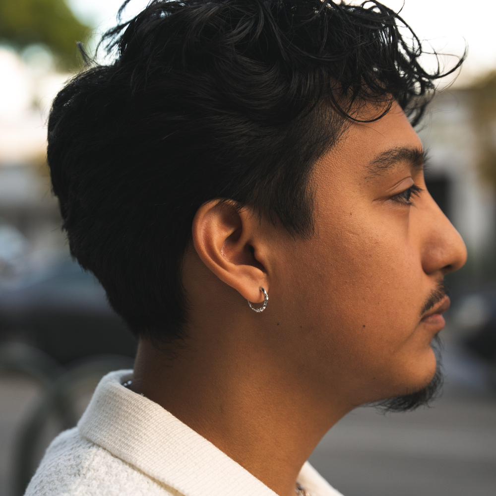 Profile of a person with dark hair and a white shirt in an outdoor setting