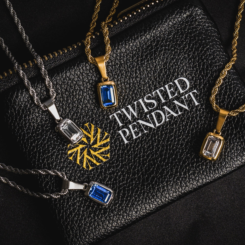 Gold, silver, and black pendants on a black leather surface with 'Twisted Pendant' branding.