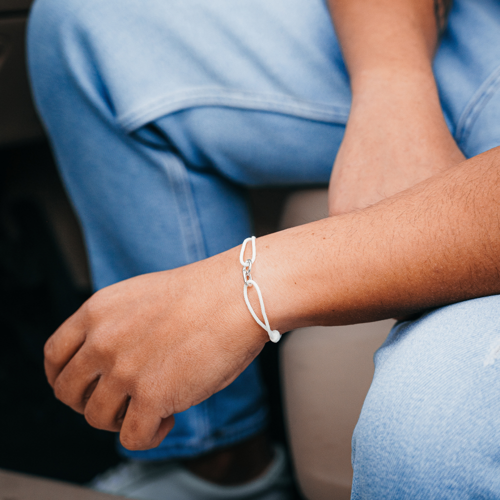 Person wearing a white bracelet on a blurred background