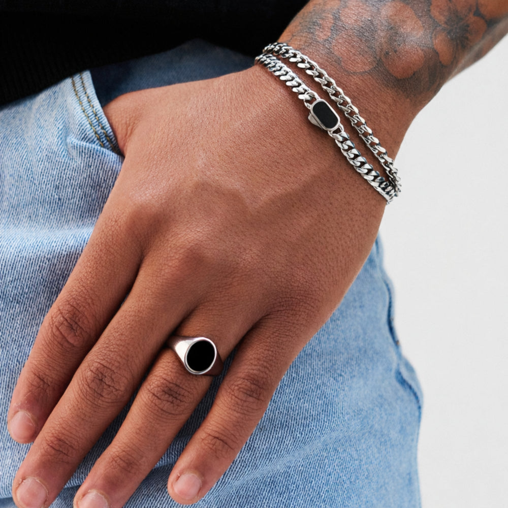 Hand wearing a silver ring and bracelet on a light blue denim background