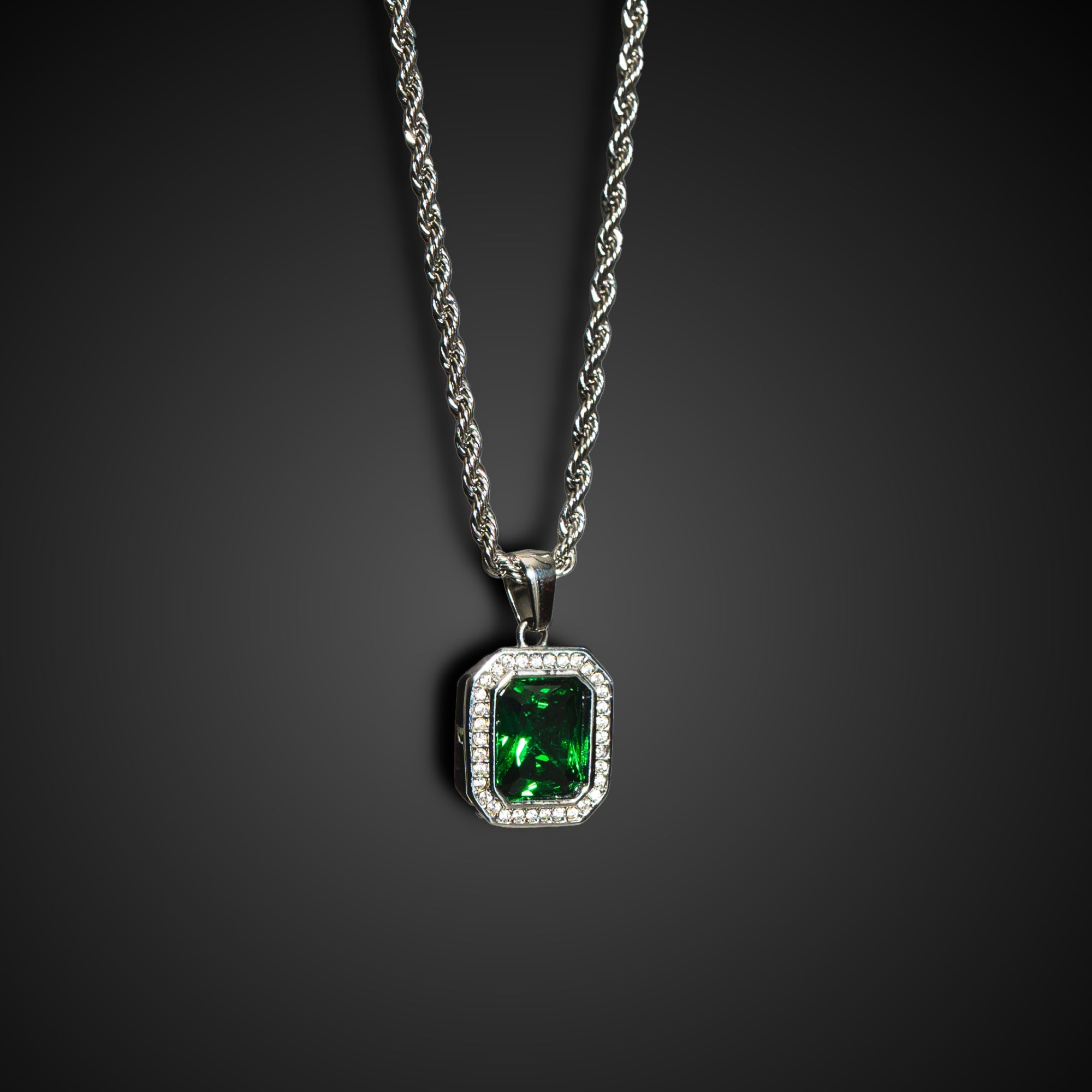 Silver necklace with a green gemstone pendant on a dark background