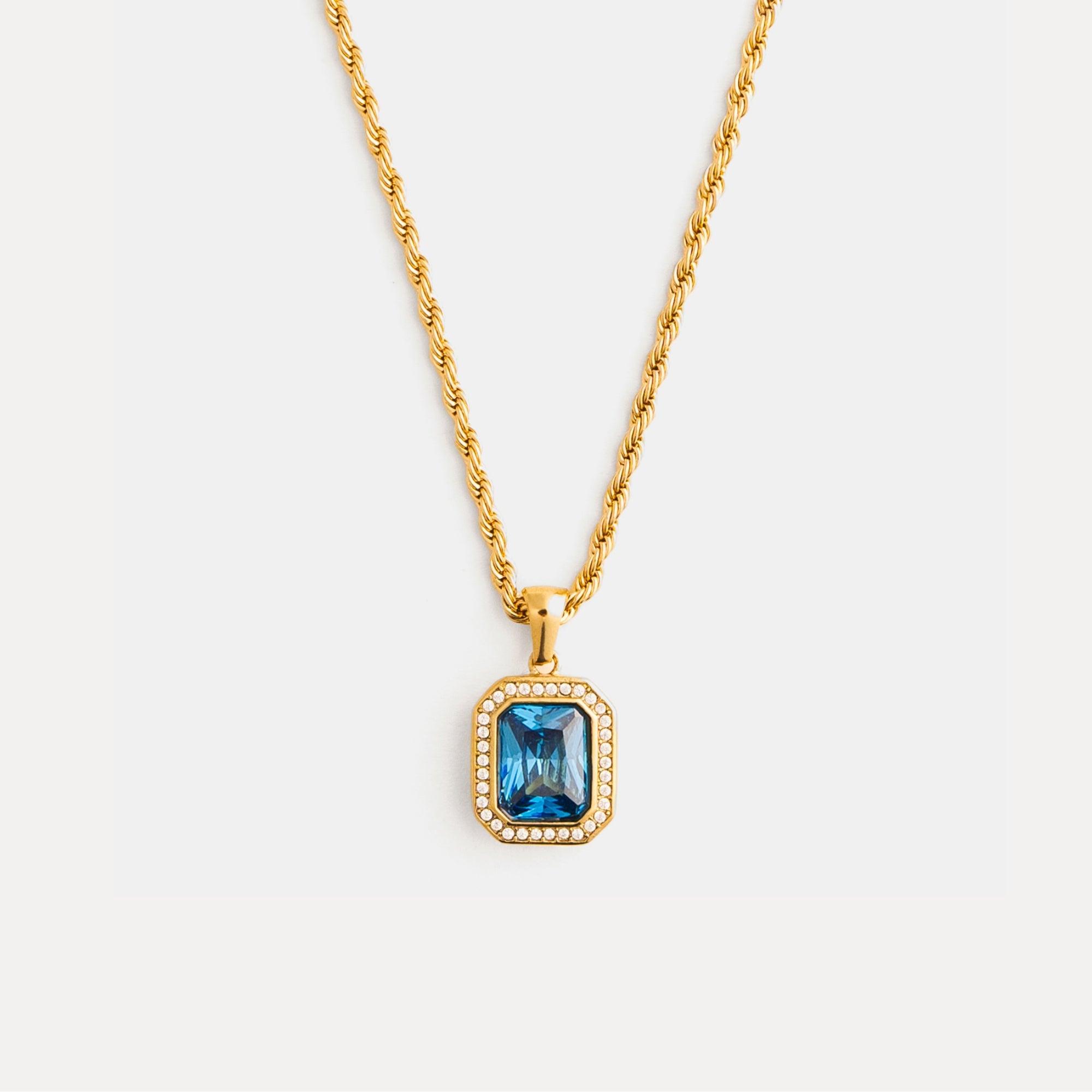 Gold necklace with a blue gemstone pendant on a white background