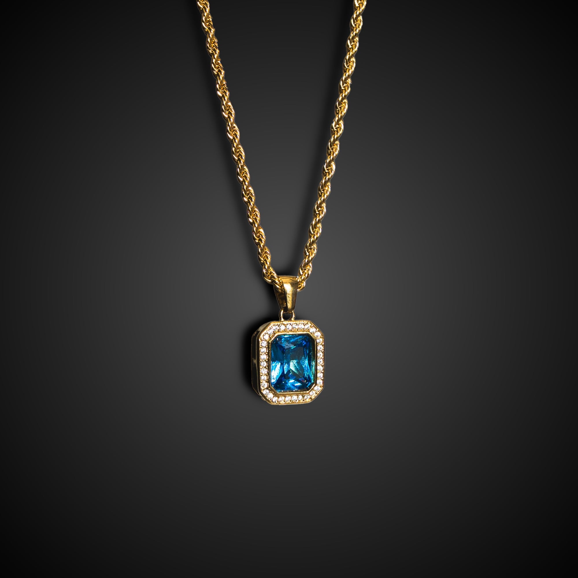 Gold necklace with a blue gemstone pendant on a dark background