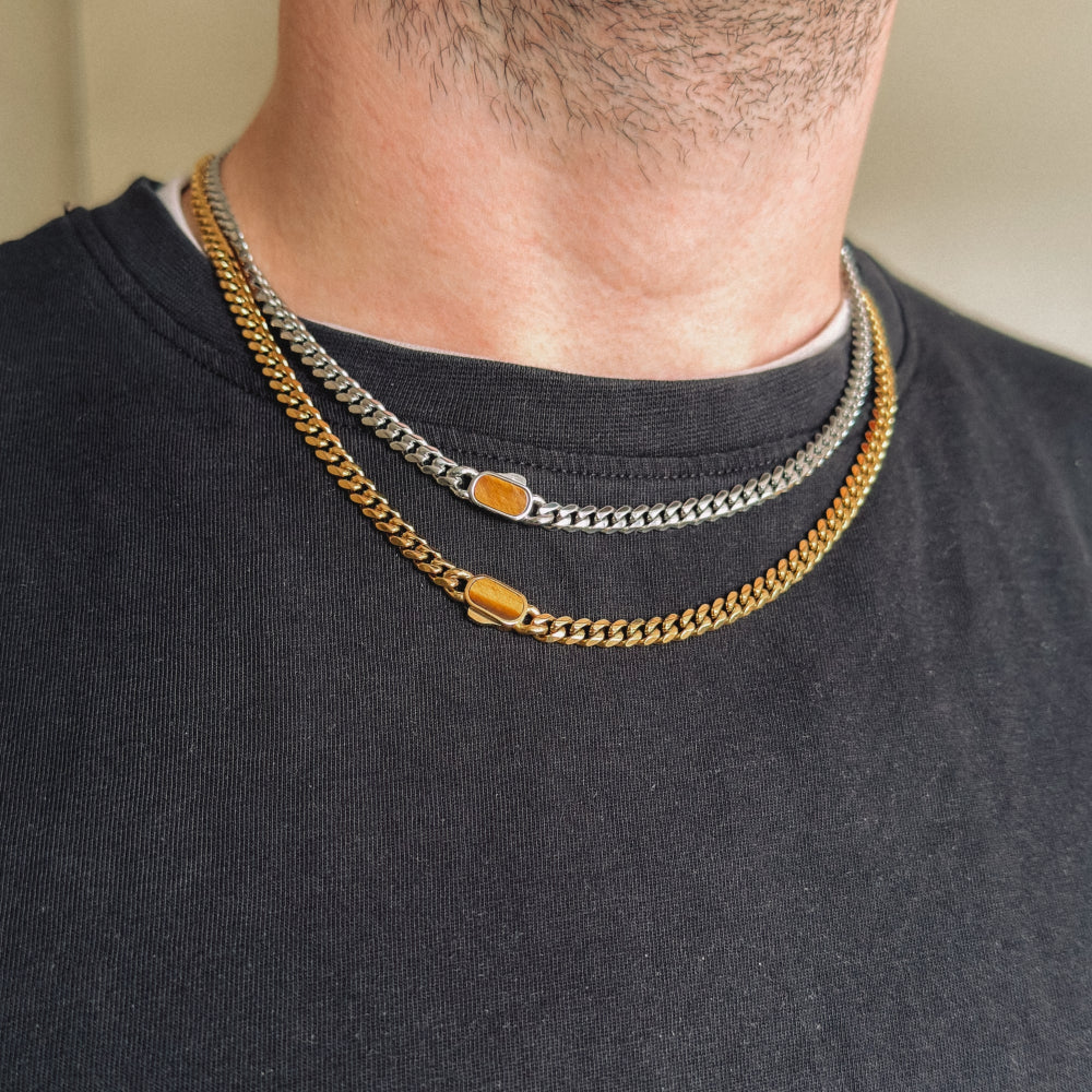 Two chain necklaces on a person wearing a black shirt.